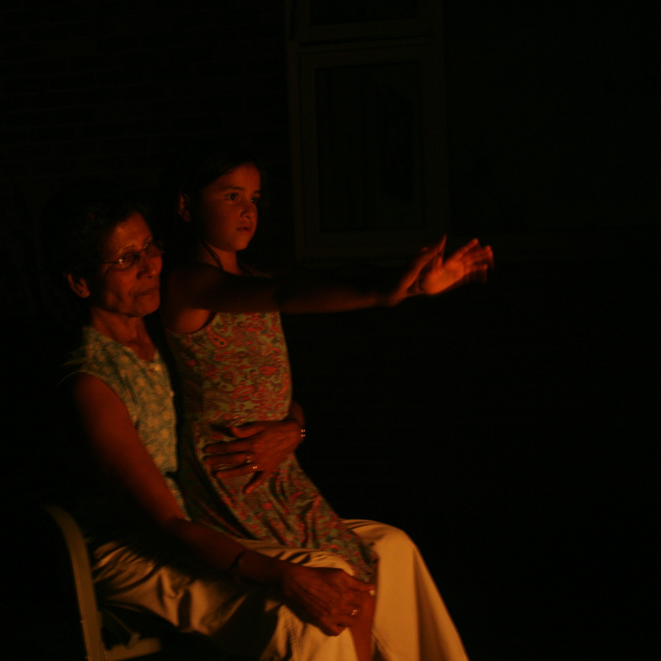 Night photo of grandmother and granddaughter warming themselves by  a fire.